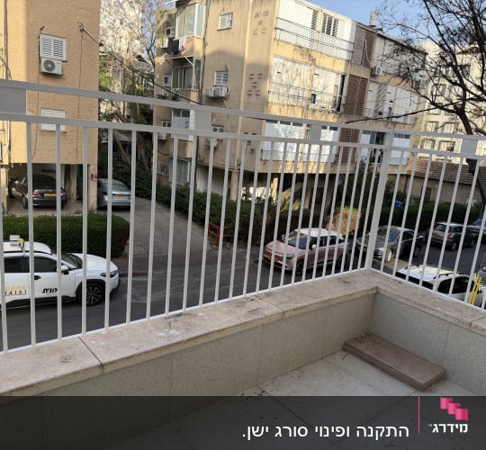 מרפסת עם מעקה מתכת מול בניינים ודירות